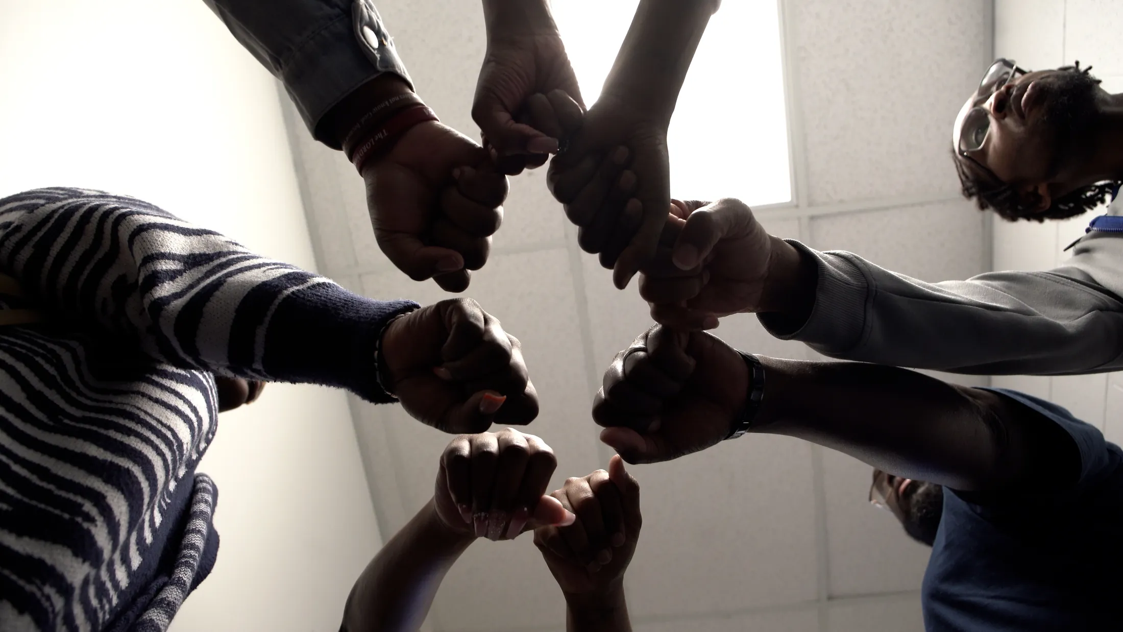 Teenagers and elders joining hands in a circle at a StoryStrong gathering in Flint, Michigan